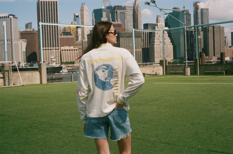 Back view of a cream terry quarter-zip pullover with a large Statue of Liberty graphic on the back.