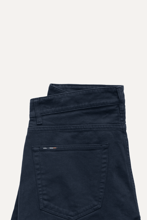 Folded navy blue jeans on a white background - Inkerman NYC