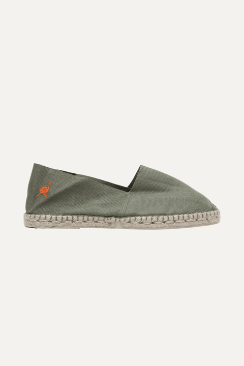 A single green canvas espadrille slip-on shoe with a braided jute sole and a small orange flamingo logo on the side, shown against a light off-white background - Inkerman NYC