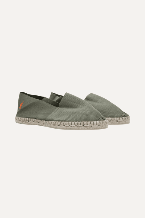 A pair of green canvas espadrille slip-on shoes with a braided jute sole and a small orange flamingo logo on the side, shown against a light off-white background - Inkerman NYC