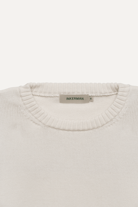 Close-up of a cream-colored knit sweater with a ribbed crew neck - Inkerman NYC
