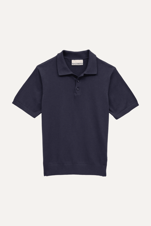 A navy blue short-sleeve polo shirt with a three-button placket, displayed flat against a light off-white background - Inkerman NYC