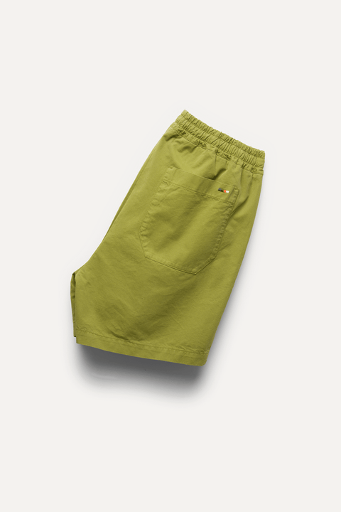 A pair of olive green shorts with an elastic waistband and a side pocket, shown on a white background with a soft drop shadow - Inkerman NYC
