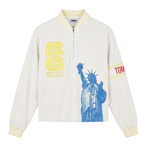 Front view of a cream terry quarter-zip pullover with FIFA embroidery, a blue Statue of Liberty graphic, and a Tombolo logo sleeve patch.

