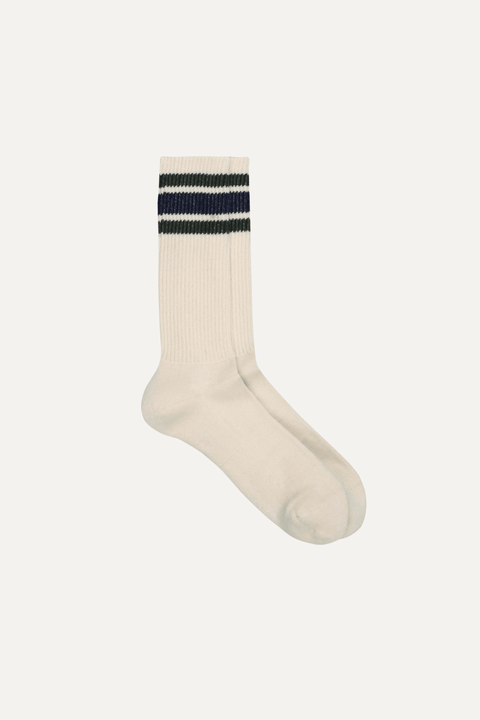 A pair of off-white ribbed crew socks with two horizontal stripes near the cuff, one dark navy and one green, set against a solid off-white background - Inkerman NYC