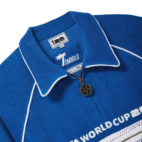 Close-up of a blue terry quarter-zip polo with FIFA World Cup 26 embroidery, a mesh zip pocket, and a soccer ball zipper pull.
